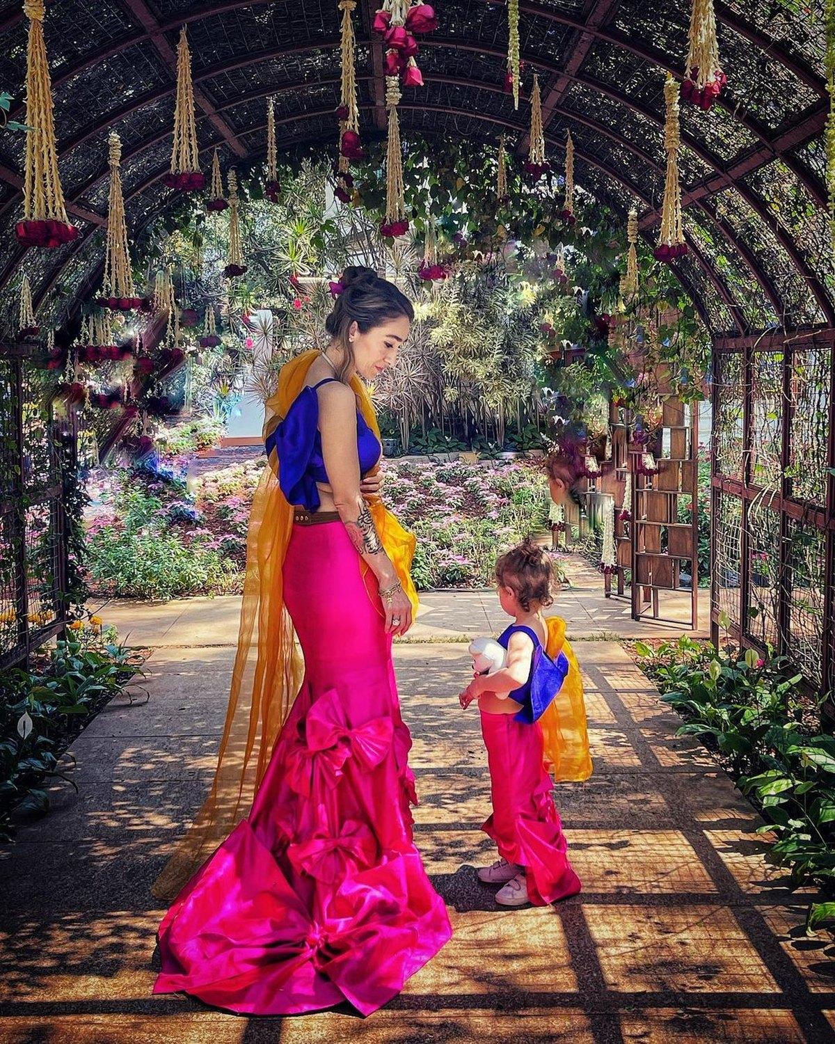 Maral Yazarloo walking with her daughter through a flowered garden arch
