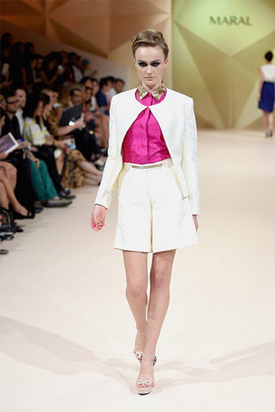 A runway look photographed beneath the MARAL show sign